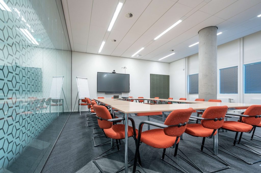 The conference room interior of a modern office with white walls and a monitor